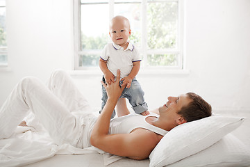 Image showing young father with his nine months old son on the bed at home