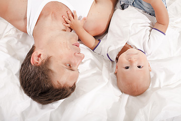 Image showing young father with his nine months old son on the bed at home