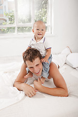 Image showing young father with his nine months old son on the bed at home