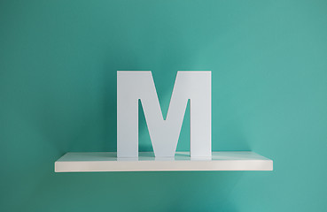 Image showing Letter M turquoise color on a white shelf.