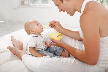 Image showing Young father with his nine months old son on the bed at home