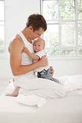 Image showing young father with his nine months old son on the bed at home