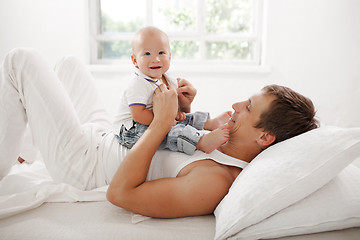 Image showing young father with his nine months old son on the bed at home