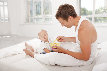 Image showing Young father with his nine months old son on the bed at home