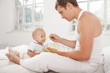 Image showing Young father with his nine months old son on the bed at home