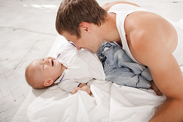 Image showing young father with his nine months old son on the bed at home