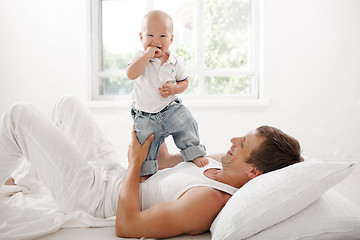 Image showing young father with his nine months old son on the bed at home