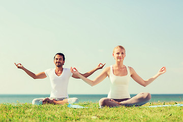 Image showing smiling couple making yoga exercises outdoors