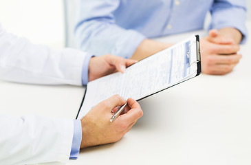 Image showing close up of male doctor and patient with clipboard