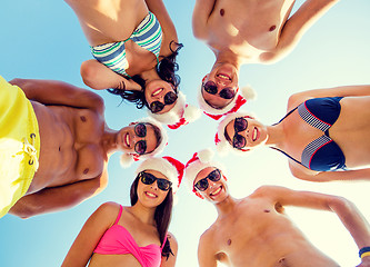 Image showing smiling friends in circle on summer beach