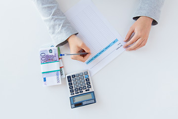 Image showing close up of hands counting money with calculator