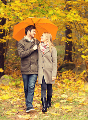 Image showing smiling couple with umbrella in autumn park