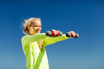 Image showing sporty woman with light dumbbells outdoors