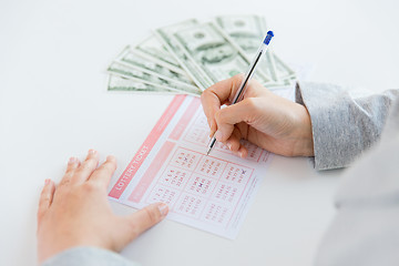 Image showing close up of hands with lottery ticket and money