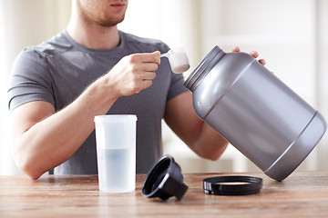 Image showing close up of man with protein shake bottle and jar