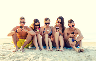 Image showing friends with smartphones on beach