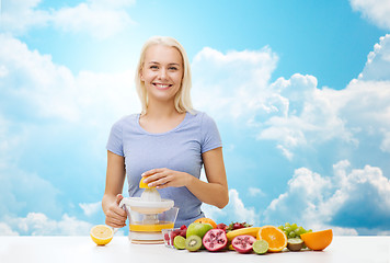 Image showing smiling woman squeezing fruit juice over sky
