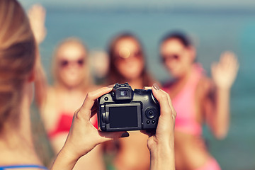 Image showing close up of smiling women photographing on beach