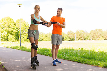 Image showing happy couple with roller skates riding outdoors