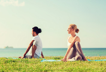 Image showing smiling couple making yoga exercises outdoors