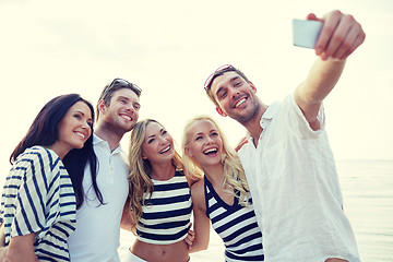 Image showing happy friends on beach and taking selfie