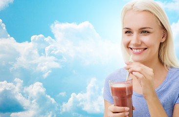 Image showing smiling woman drinking juice or shake over sky