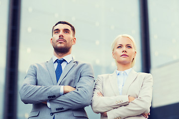 Image showing serious businessmen standing over office building