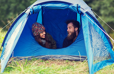 Image showing smiling couple of tourists looking out from tent