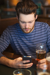 Image showing man with smartphone drinking beer at bar