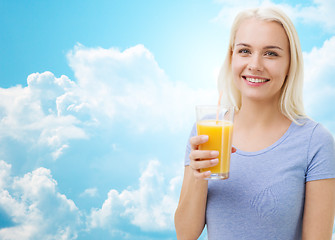 Image showing smiling woman drinking orange juice over sky