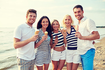 Image showing smiling friends eating ice cream on beach