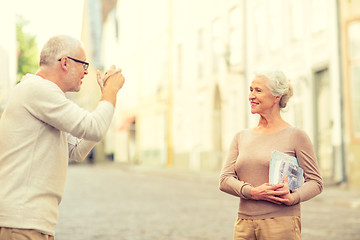 Image showing senior couple photographing on city street