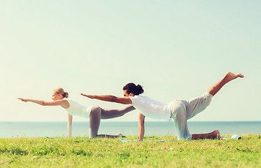 Image showing smiling couple making yoga exercises outdoors