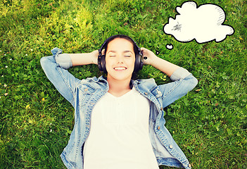 Image showing smiling young girl in headphones lying on grass