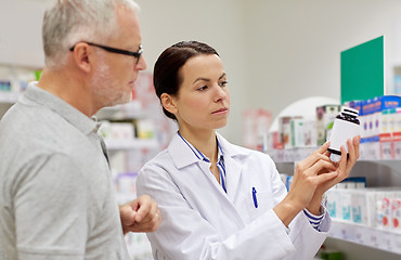 Image showing pharmacist showing drug to senior man at pharmacy