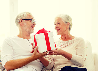 Image showing happy senior couple with gift box at home