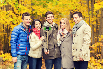 Image showing smiling friends with smartphone in city park