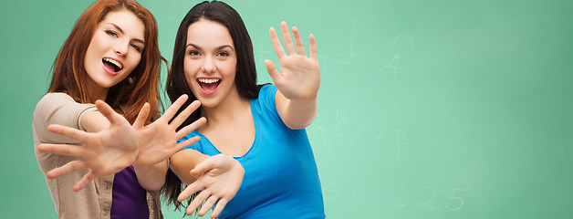 Image showing happy student girls showing their palms over green