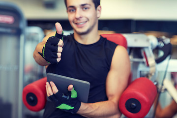 Image showing young man with tablet pc showing thumbs up in gym