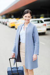 Image showing smiling young woman with travel bag over taxi