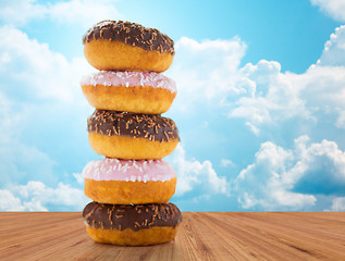 Image showing close up of glazed donuts pile over blue sky