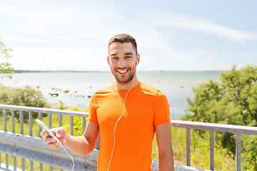 Image showing smiling young man with smartphone and earphones