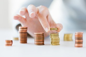 Image showing close up of female hand putting coins into columns