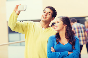 Image showing group of smiling students with smartphone outdoors