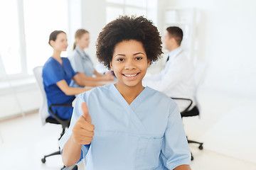 Image showing happy female doctor or nurse showing thumbs up