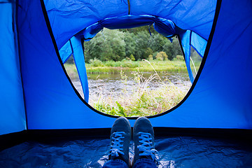 Image showing close up of camper legs lying near tent entrance