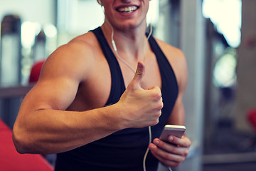 Image showing happy man with smartphone and earphones in gym