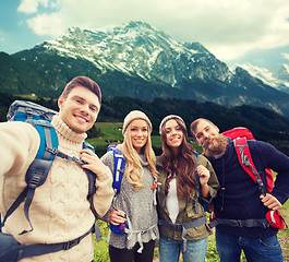 Image showing group of smiling friends with backpacks hiking