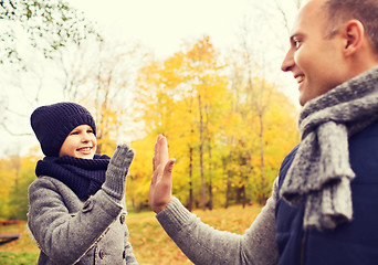 Image showing happy father and son making high five in park