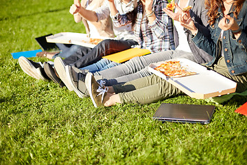 Image showing close up of teenage students eating pizza on grass